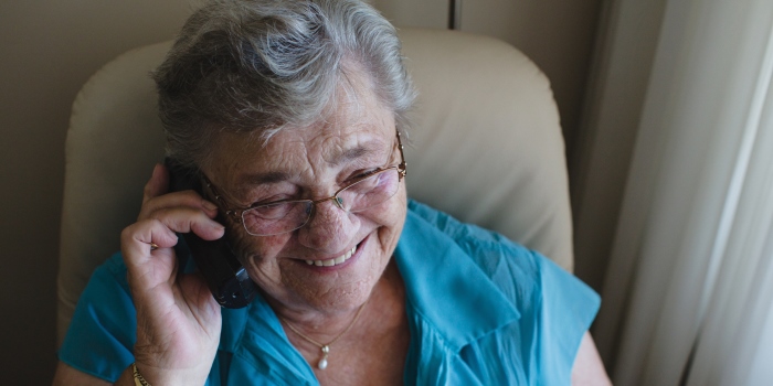 Happy older woman talking on landline phone at home